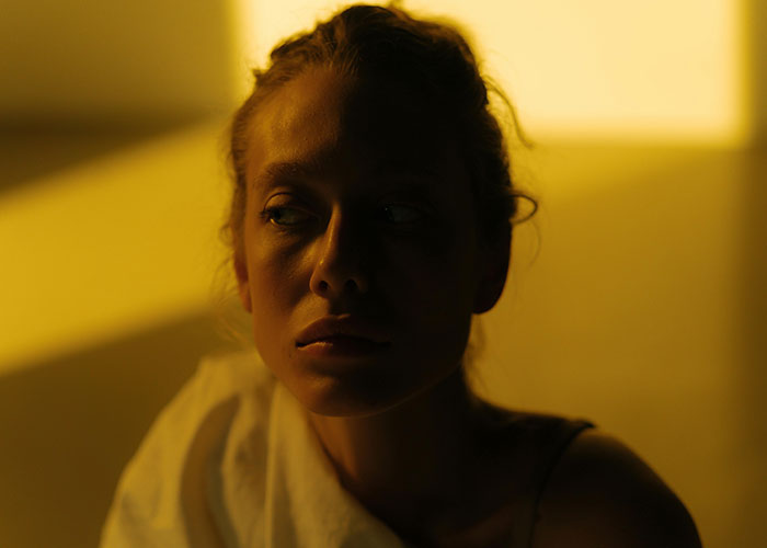 Young woman with a serious expression in low light, reflecting on emotional pain linked to cheating stories.