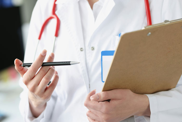 Doctor in white coat holding a clipboard and pen, symbolizing hospital mistakes and medical errors in healthcare settings.