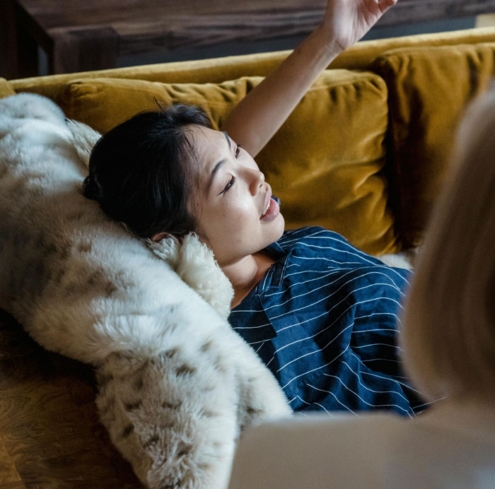 Woman lying on a couch speaking during therapy session, illustrating key differences between men and women in communication. - 25