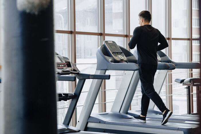Man in black workout clothes jogging on treadmill in a gym illustrating wild to disgusting things people did in public.