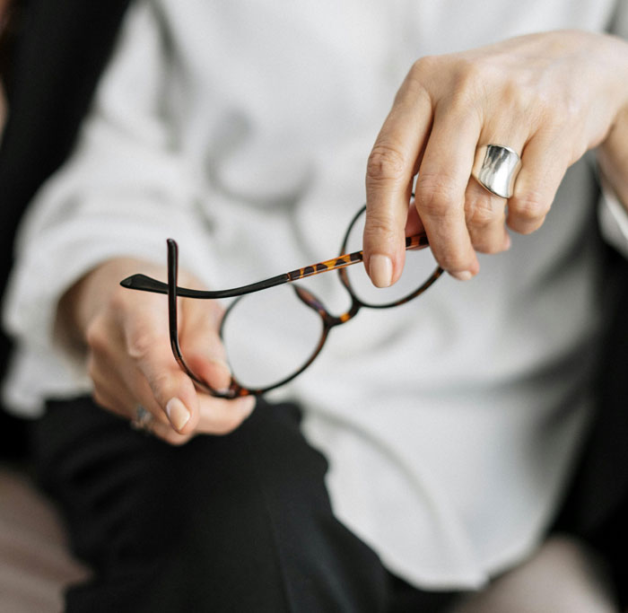 Person holding tortoiseshell glasses with focus on hands and ring, illustrating therapists' insights on differences between men and women. - 30
