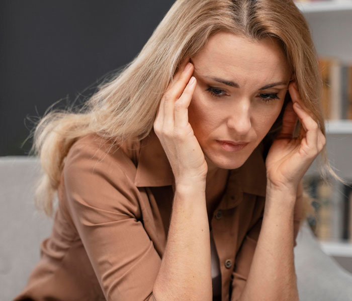 Worried woman holding her head, seeking advice after CPS threats from mother-in-law in a home setting. Worried woman holding her head, seeking advice after CPS threats from mother-in-law in a home setting.
