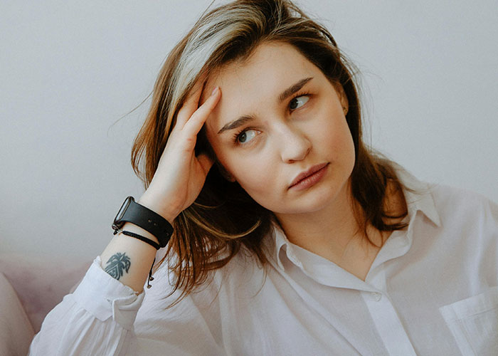 Young woman rethinking her relationship after noticing red-flag behavior, appearing worried and fearful in a casual setting.