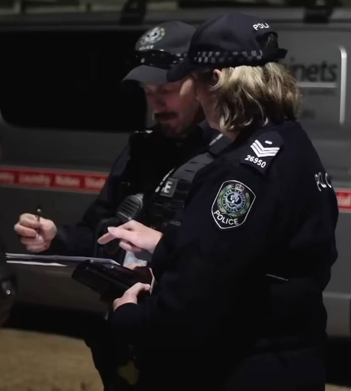 Two police officers at a nighttime crime scene investigating after reality star charged with murder arrest.