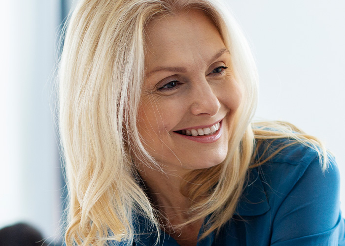Smiling woman in a blue shirt representing managers and HR handling ridiculous complaints from employees in an office setting.