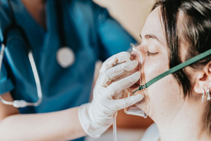 Patient wearing oxygen mask receiving care from healthcare worker illustrating terrifying hospital mistakes in treatment.