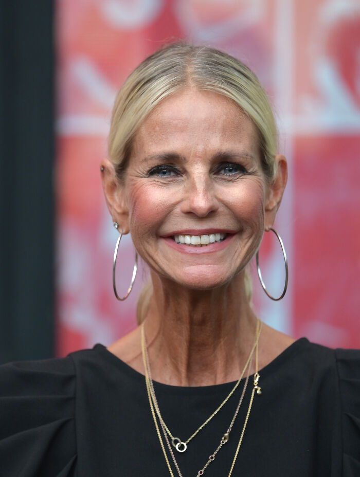 Ulrika Jonsson smiling with hoop earrings and layered necklaces, addressing trolls over her over-tanned face online.
