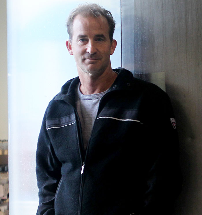 Man in casual jacket standing indoors near window, related to Coldplay HR exec mortgage news story. - 3