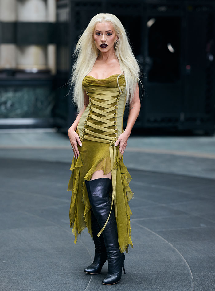 Woman resembling Christina Aguilera in a green corset dress and thigh-high black boots during a public appearance sparking health concerns. Woman resembling Christina Aguilera in a green corset dress and thigh-high black boots during a public appearance sparking health concerns.