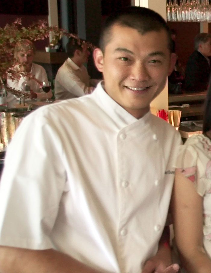 Chef in white uniform smiling inside restaurant after controversy involving micro influencer follower count.