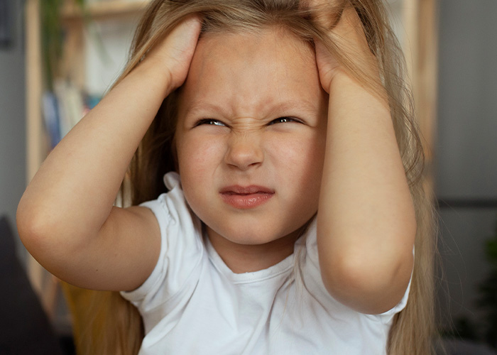 Young girl holding her head with a frustrated expression illustrating parents revealing hilarious lies they tell their kids.