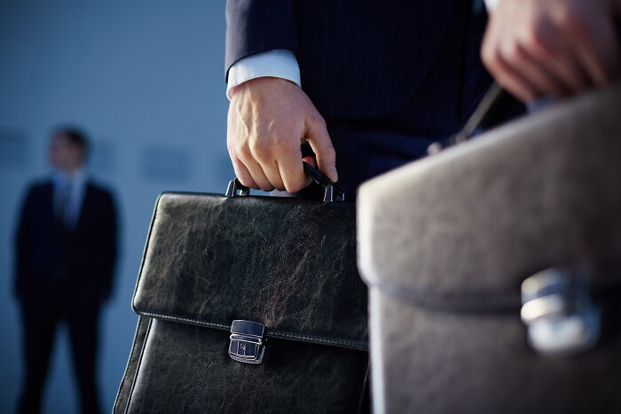 Two people in business suits holding briefcases, illustrating habits some netizens find really creepy. - 32