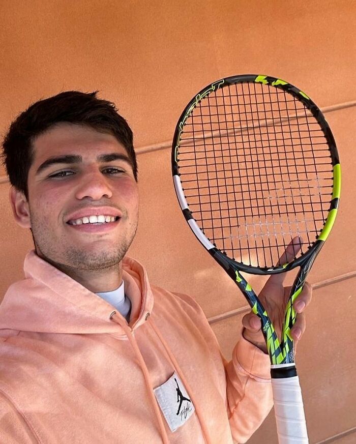 Young man smiling and holding a tennis racket, related to celebrities that many people love but can't stand topic.