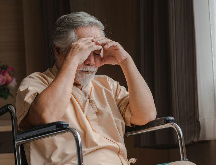 Hombre mayor en silla de ruedas con expresión preocupada simbolizando errores terribles en hospitales.