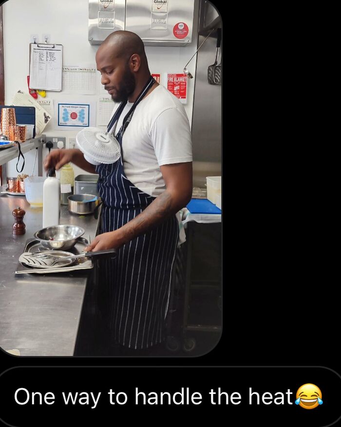Chef in a kitchen wearing apron with portable fan around neck to handle heat, relatable chef meme humor well-done.