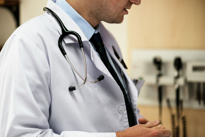 Doctor en bata blanca con estetoscopio en hospital, relacionado con hospitales y errores médicos terribles.