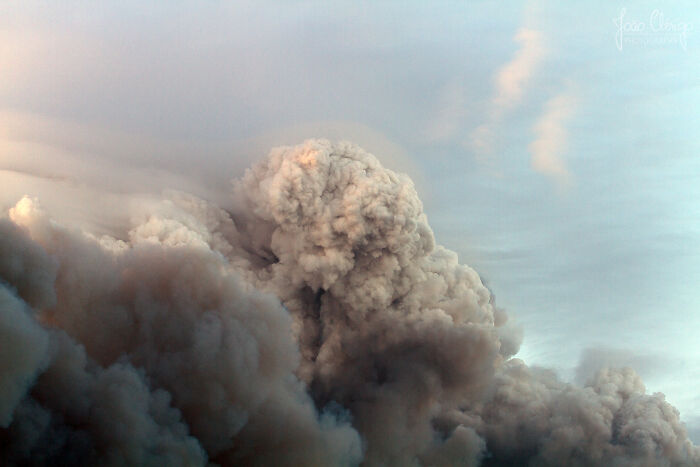 Thick smoke clouds rising during one of the most catastrophic wildfires in recent history under a blue sky.