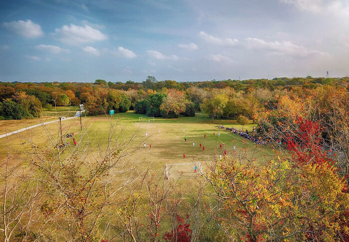 A scenic park with a soccer game in progress surrounded by colorful fall trees in one of the best places to live in the USA.