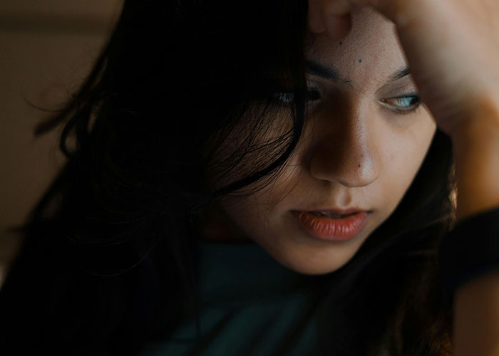 Worried woman rethinks her relationship after a red-flag argument, showing fear and emotional distress in dim lighting.