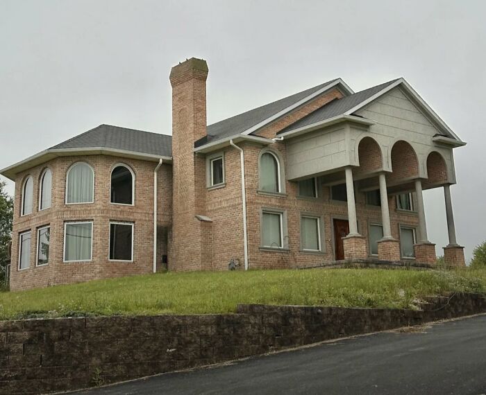 Large brick home with mismatched windows and arches, an example of people trying to be creative with their homes and failed designs.