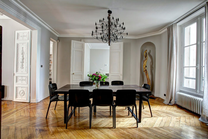 Modern dining room with black chairs and chandelier, illustrating oldschool home trends millennials are over.