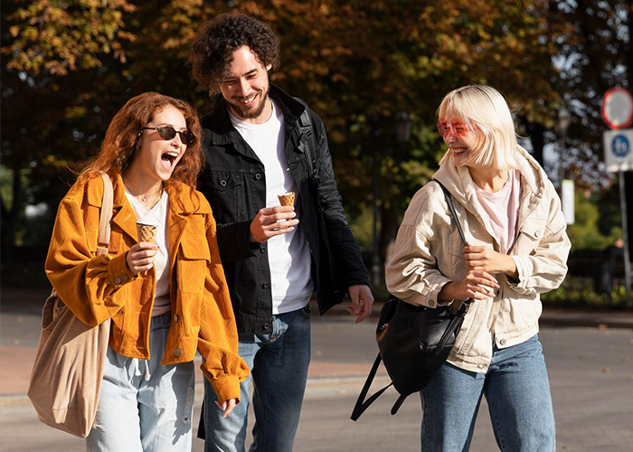 Three friends enjoying ice cream outdoors, sharing laughs and candid moments, illustrating facts people are tired of explaining.