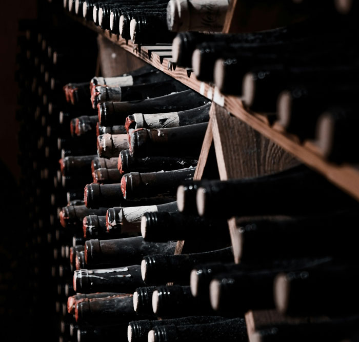 Rows of dusty wine bottles stored in a wooden rack, illustrating unexpected things people learned about the rich.
