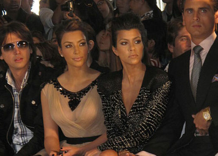 Four people at a public event, with two women representing the KarJenner clan sitting in the center, dressed in stylish outfits. - 7