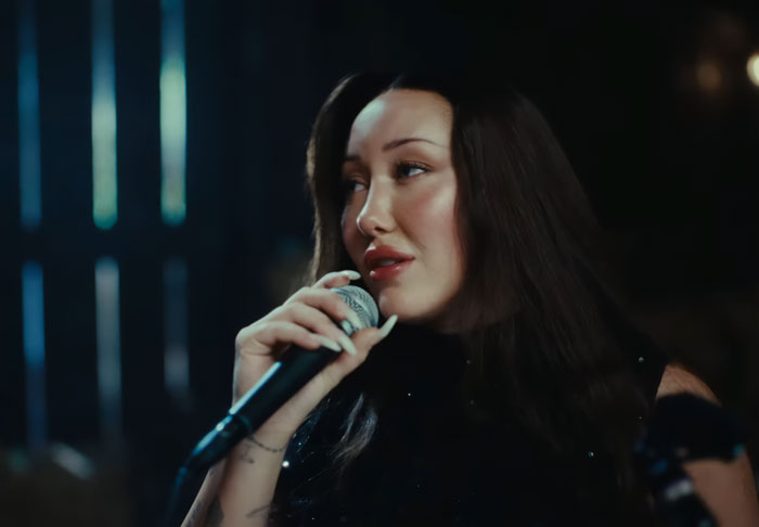 Noah Cyrus holding a microphone during a performance, noted for her dramatic transformation sparking plastic surgery rumors. Noah Cyrus holding a microphone during a performance, noted for her dramatic transformation sparking plastic surgery rumors.
