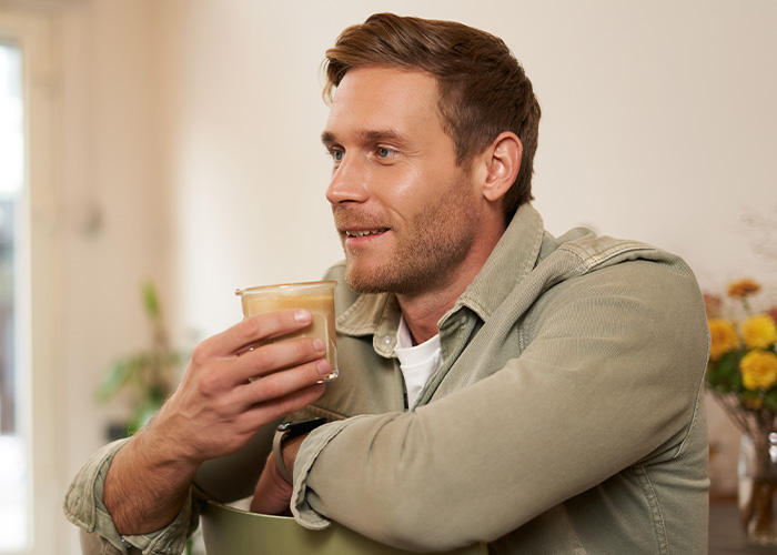 Man in casual shirt holding coffee cup, smiling while reflecting on former employees revealing crazy secrets. - 2
