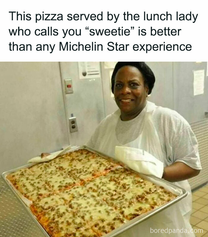 Lunch lady smiling while holding a large tray of pizza, nostalgic meme for those who grew up with Tamagotchis and VHS tapes.