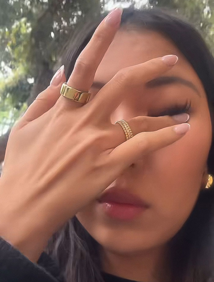 Woman with gold rings covering part of her face outdoors, related to chef and micro influencer follower count controversy.