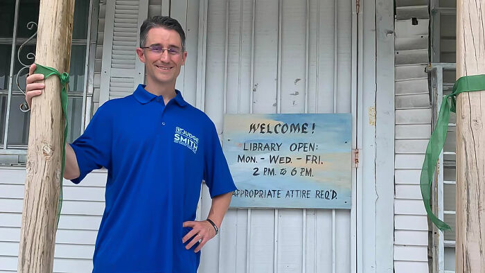Man in blue shirt standing by wooden posts outside a building, illustrating consequences of stupidity and lost jobs.
