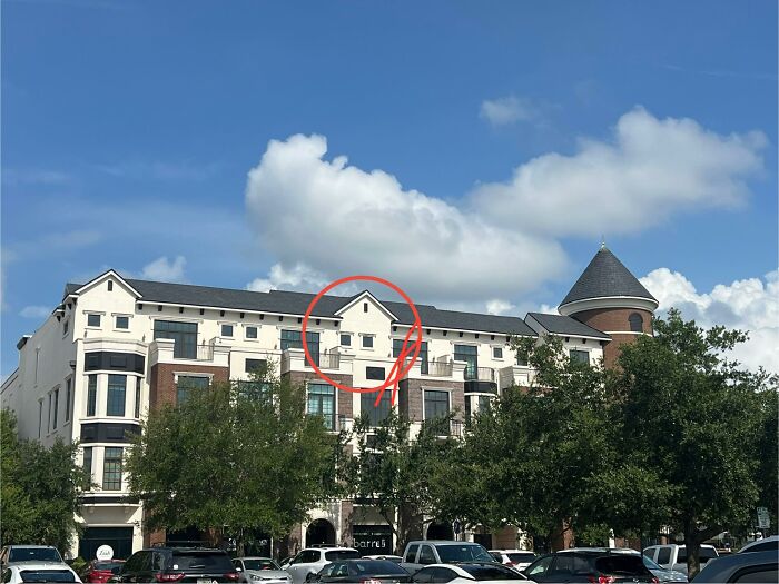 Apartment building with a small, oddly placed window circled, showing a creative home design fail under blue sky.