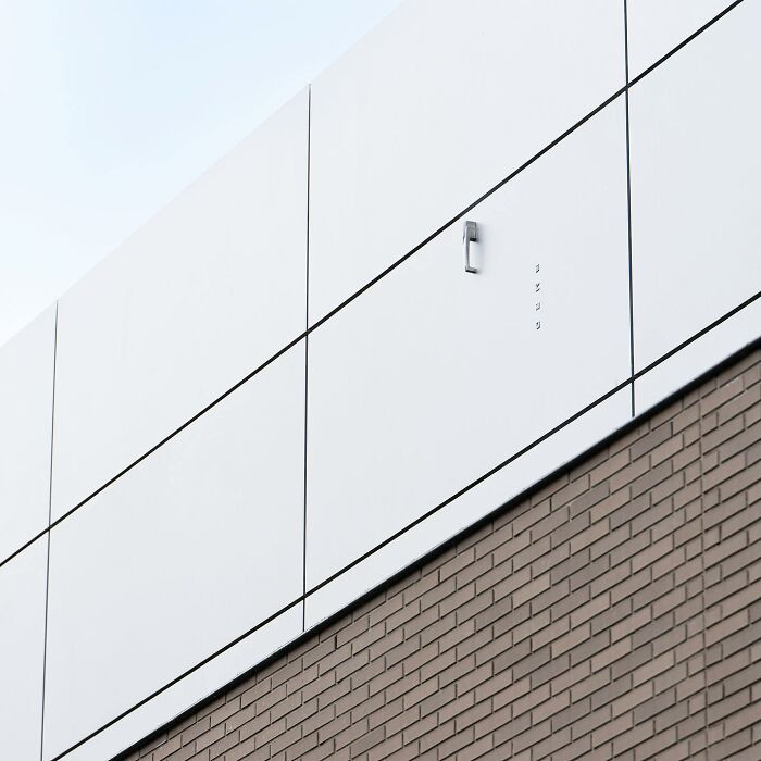 Minimalist public space featuring clever street art with a metal phone handset mounted on a white wall panel.