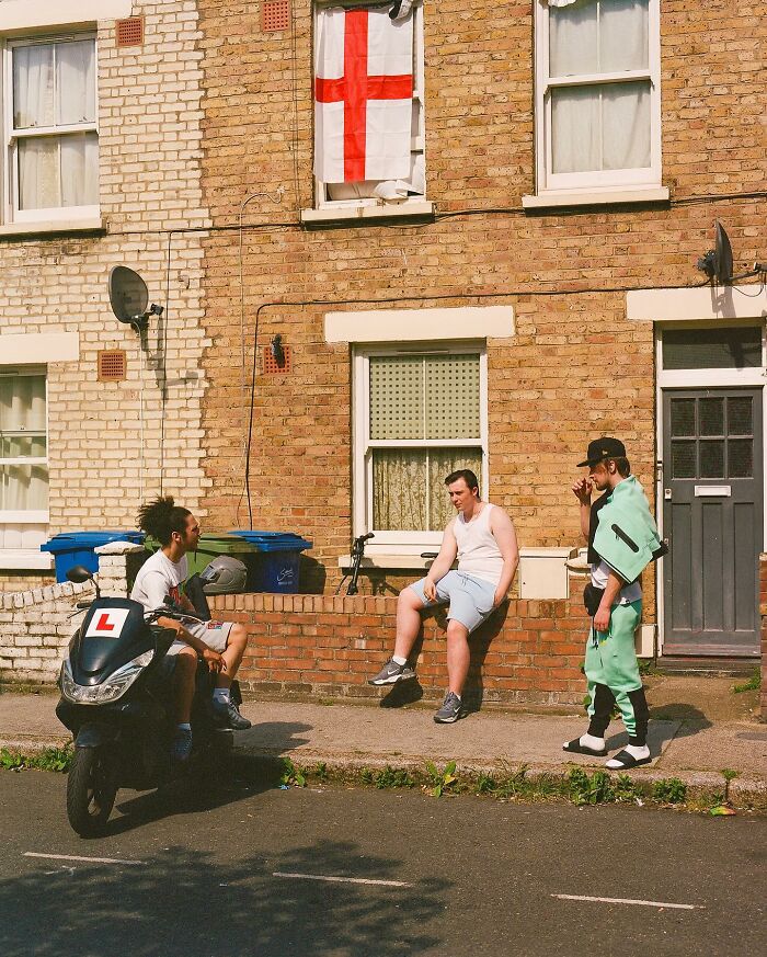 Three young men socializing outside a brick London home, capturing authentic London street life in honest photos.
