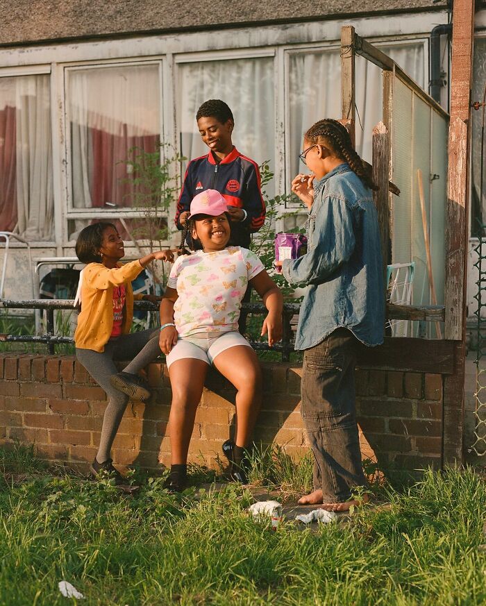 Four children socializing outdoors in London, captured in an honest photo showcasing everyday street life and community spirit.