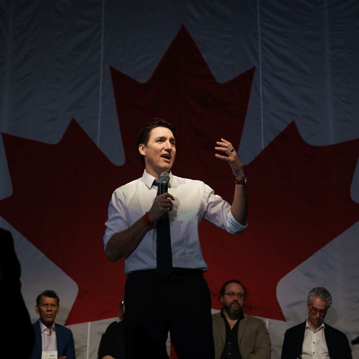 Justin Trudeau speaking at an event with a large Canadian flag in the background amid romance rumors with Katy Perry. Justin Trudeau speaking at an event with a large Canadian flag in the background amid romance rumors with Katy Perry.