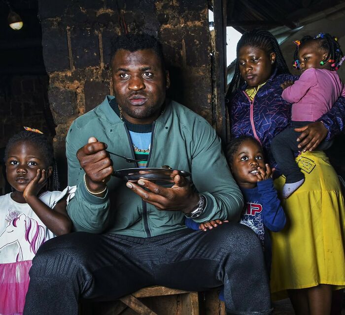 Man eating a meal with family in a modest home, portraying a story of from poverty to super wealthy transformation.