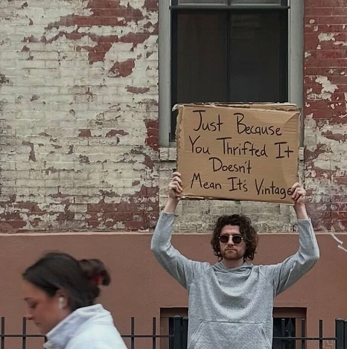 Man holding a sign with a humorous message about thrifting, representing the Dude With The Sign series outdoors.