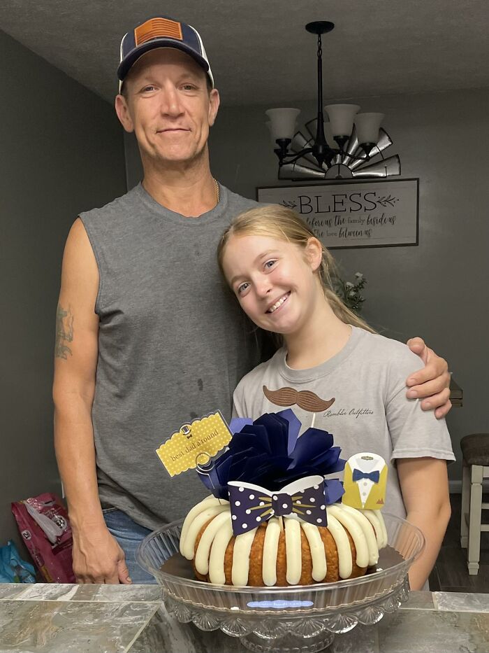 Man and girl smiling behind a decorated cake, captured in a candid moment of unbelievable luck and happiness.
