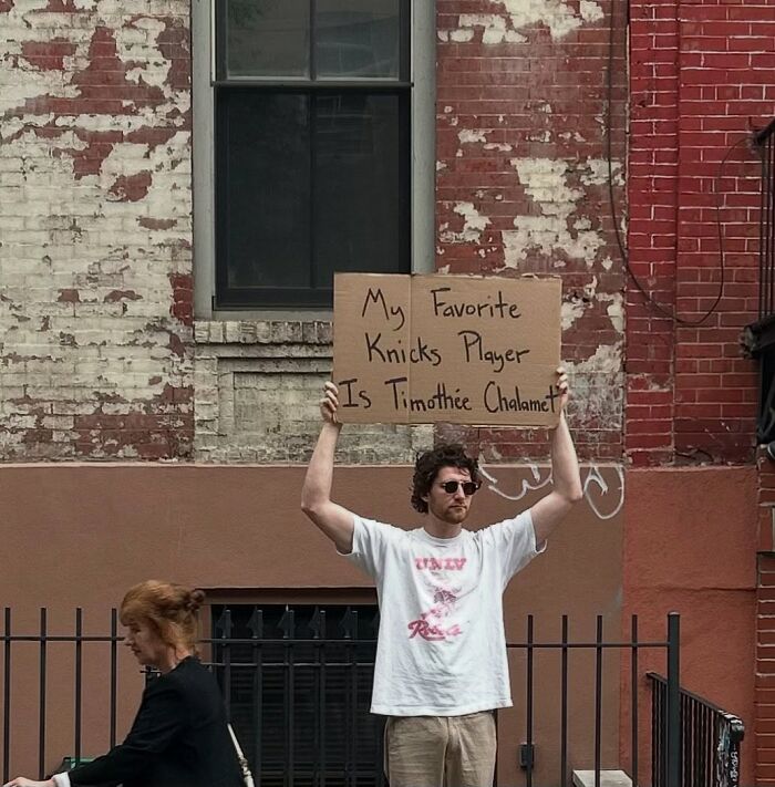 Man holding a cardboard sign with a humorous message, representing Dude With The Sign relatable commentary.