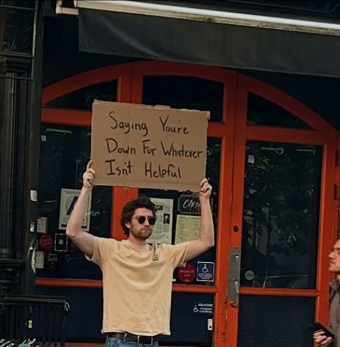 Man holding a cardboard sign on the street with a message, representing Dude With The Sign's relatable statements.