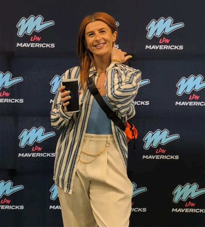 Person smiling and holding a cup at an event with a backdrop, unrelated to European pharmacies or bottles. Person smiling and holding a cup at an event with a backdrop, unrelated to European pharmacies or bottles.