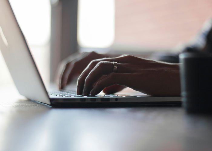Hands typing on a laptop keyboard, illustrating a guy messaging after every client as instructed by his boss. - 9