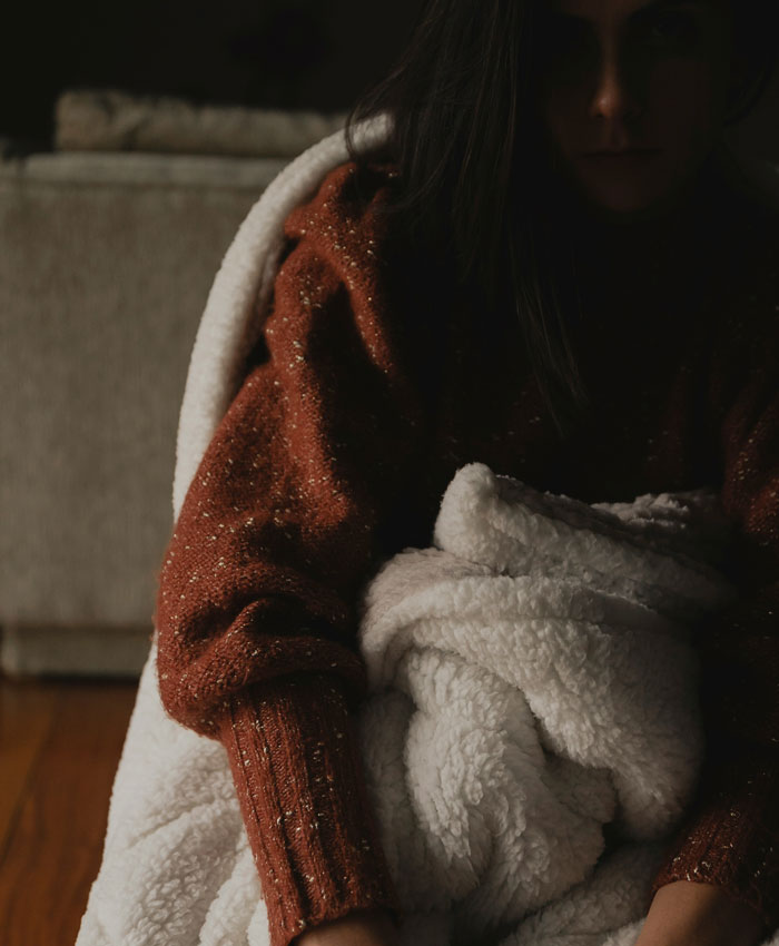 Millennial wrapped in a cozy blanket at home, reflecting on oldschool home trends millennials are over.