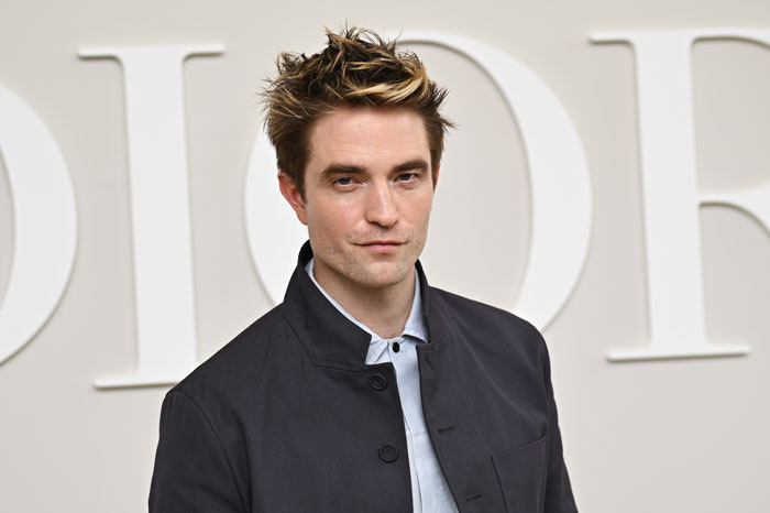 Robert Pattinson posing at an event, dressed in a black jacket, related to Twilight intimate scene discussion.