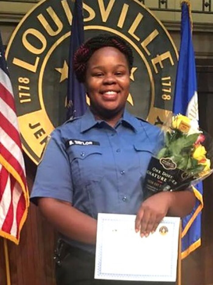 Smiling woman in uniform holding flowers and a certificate, representing consequences of stupidity and job loss.