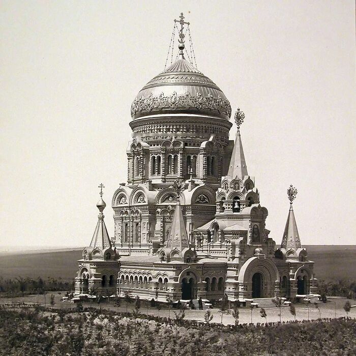 Ornate old architecture featuring a large domed church with intricate details and multiple spires in a rural setting.