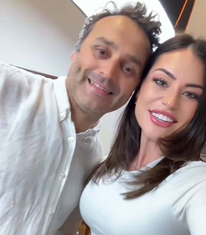 Woman with 3 kids smiling after mommy makeover, showcasing stunning results and confidence in a bright indoor setting.